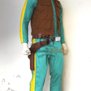 Puede incluir: Un disfraz que presenta un mono turquesa con una raya amarilla en el lateral, un chaleco marrón con bolsillos y un cinturón marrón con una funda. El disfraz se exhibe en un maniquí.