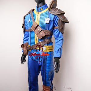 May include: Blue and yellow jumpsuit with brown leather accents, including shoulder pads, a belt, and pouches. The costume features the number 33 on the chest and is displayed on a mannequin.