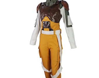 May include: A yellow jumpsuit with white straps and brown leather accents. The jumpsuit has a high waist and cargo pockets. The model is wearing a white and green shirt underneath the jumpsuit.
