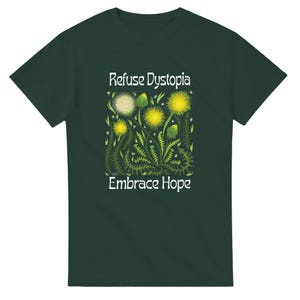 May include: Dark green t-shirt featuring a floral design with yellow flowers and green leaves. The text "Refuse Dystopia" and "Embrace Hope" are printed in white. The shirt is a crew neck style.