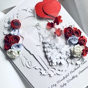 May include: A white card with a red heart, red and white flowers, and a silhouette of a bride and groom. The card reads "To My Wonderful Husband Peter On Our Ruby Wedding Anniversary".