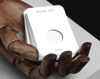 May include: A white card with the text "THE MOON" and the Roman numeral "VIII" printed on it. The card has a crescent moon shape cut out of the centre.