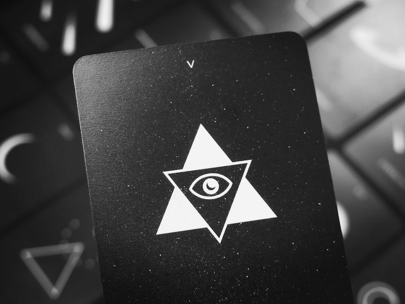 May include: Black card with a white triangle containing an eye and the letter "V" in the top right corner.