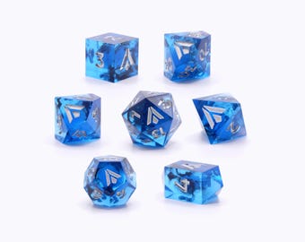 May include: Set of seven blue dice with silver metallic numbers and a silver metallic symbol on each face. The dice are made of clear blue glass with a swirling pattern.