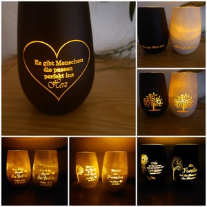 Könnte beinhalten: Sortiment an Glas-Kerzenhaltern mit verschiedenen Designs und Sprüchen. Die Kerzenhalter sind angezündet und leuchten. Einige der Sprüche sind "Es gibt Menschen die passen perfekt ins Herz", "Mit dir ist alles möglich", "Die Besten", "Die Familie", "Freundschaft" und "Mit Gott alles gut".