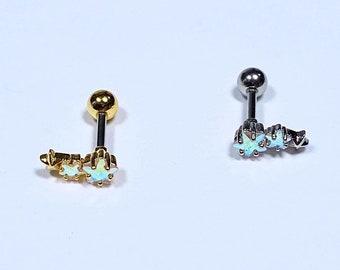 May include: Two cartilage earrings with a row of three opal star charms. The earring on the left is gold and the earring on the right is silver.