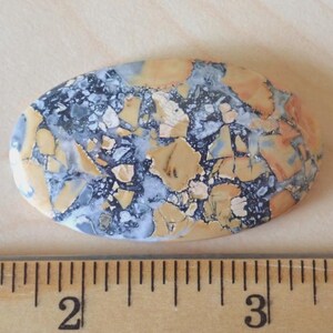 Maligano Jasper Cabochon, Creamy Yellowish White & Blueish Gray, From a Veteran Owned Studio sitting next to a wooden ruler for scale.