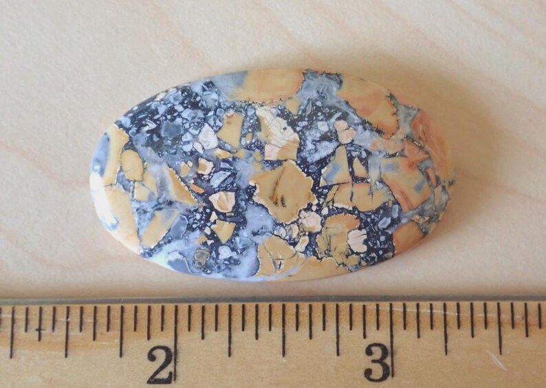 Maligano Jasper Cabochon, Creamy Yellowish White & Blueish Gray, From a Veteran Owned Studio sitting next to a wooden ruler for scale.