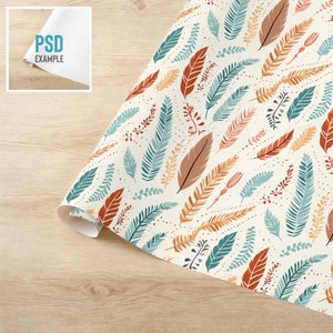 May include: A white wrapping paper with a repeating pattern of teal, orange, and brown leaves and branches. The background is a light cream color with small white dots.
