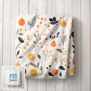 May include: White fabric with a repeating pattern of orange citrus fruit, black leaves, and small yellow dots. The fabric is folded and draped over a white wooden surface.