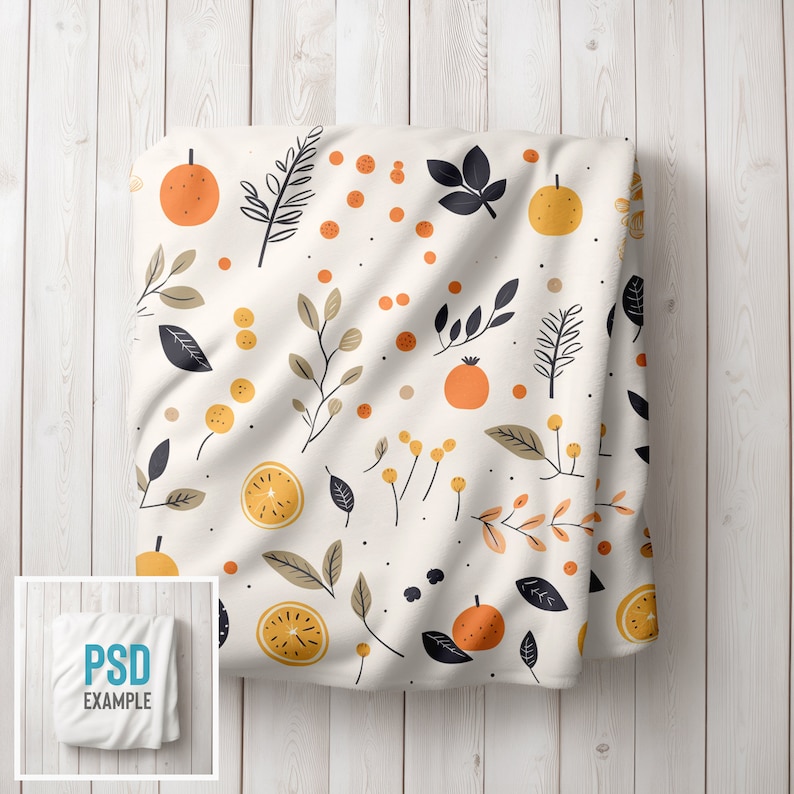 May include: White fabric with a repeating pattern of orange citrus fruit, black leaves, and small yellow dots. The fabric is folded and draped over a white wooden surface.