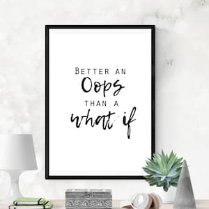 May include: Black and white framed print with the quote "Better an Oops than a what if" on a white background. The print is displayed on a wooden shelf with a decorative box, a plant, and headphones.