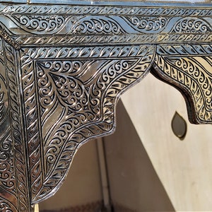 May include: A silver and gold ornate mirror with intricate floral designs. The mirror has a rectangular frame with a decorative arch at the top.
