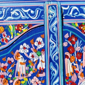 May include: A blue wooden panel featuring intricate floral and geometric designs painted in vibrant colours, including pink, yellow, orange, and white.