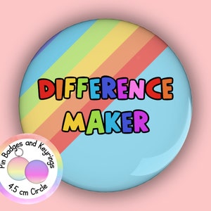May include: A circular pin badge featuring a diagonal rainbow stripe pattern against a light blue background. The text "DIFFERENCE MAKER" is printed in bold, multi-coloured letters across the centre. A small circular label indicates a 4.5 cm size.