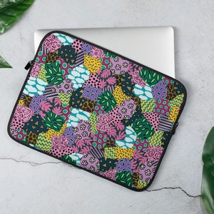 May include: A laptop sleeve with a colorful patchwork design featuring pink, green, yellow, and blue geometric shapes and floral patterns.