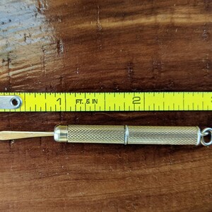 This rare 9K solid gold retractable toothpick—a unique and sophisticated blend of functionality and refinement. making a perfect gifts for luxury EDC (everyday carry) enthusiasts, or those who appreciate unconventional fine jewelry. This handcrafted piece merges discreet utility with old-world craftsmanship.  An unforgettable conversation starter for fans of unique gadgets, historical pocket accessories.