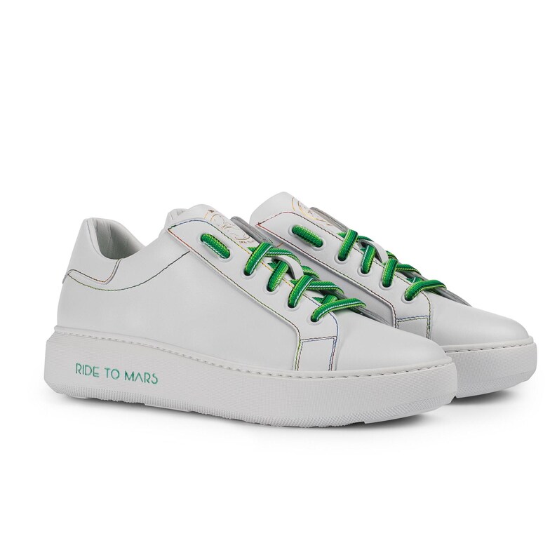 Puede incluir: Zapatillas bajas de cuero blanco con cordones verdes y un dise&ntilde;o de arco&iacute;ris en el lateral. Las zapatillas tienen una suela de goma blanca con el texto "RIDE TO MARS" impreso en el lateral.