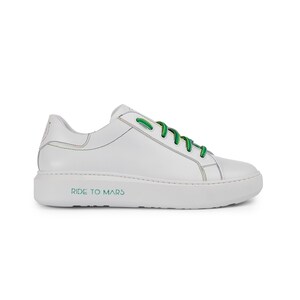 Puede incluir: Zapatillas bajas de cuero blanco con cordones verdes y un contorno de arco&iacute;ris. La suela tiene el texto "RIDE TO MARS" impreso.