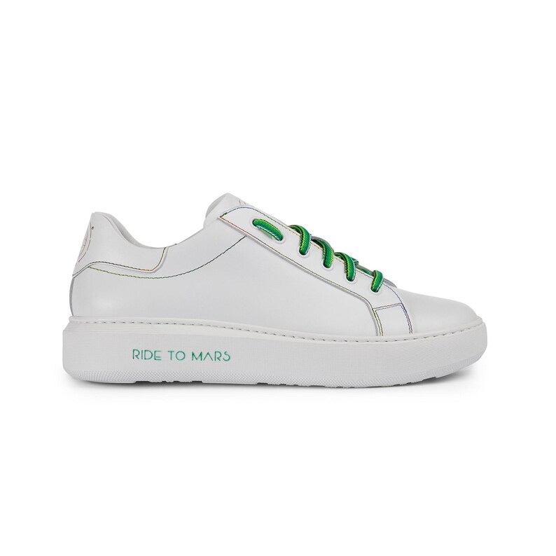 Puede incluir: Zapatillas bajas de cuero blanco con cordones verdes y un contorno de arco&iacute;ris. La suela tiene el texto "RIDE TO MARS" impreso.