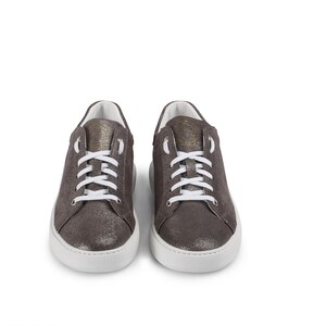 Puede incluir: Un par de zapatillas bajas de ante gris con cordones blancos y suela de goma blanca.