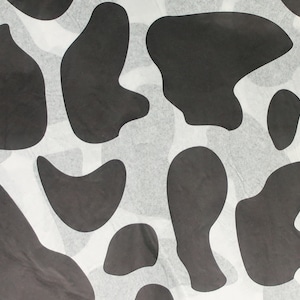 May include: A repeating pattern of black and white cow spots. The abstract shapes are irregularly shaped and scattered across the surface. The background is a light, textured white.