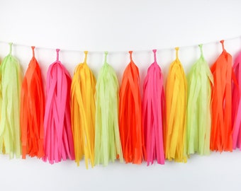 May include: A colorful tissue paper tassel garland with alternating colors of green, yellow, orange, and pink. The garland is strung on a white string and is perfect for adding a festive touch to any party or celebration.