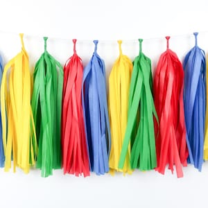 May include: A colorful tissue paper tassel garland with red, yellow, green, and blue tassels. The garland is strung on a white string and is perfect for adding a festive touch to any party or celebration.