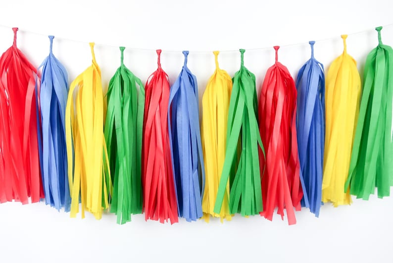 May include: A colorful tissue paper tassel garland with red, yellow, green, and blue tassels. The garland is strung on a white string and is perfect for adding a festive touch to any party or celebration.