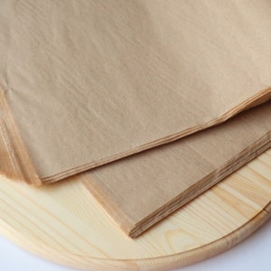 May include: A stack of brown tissue paper on a round wooden surface.