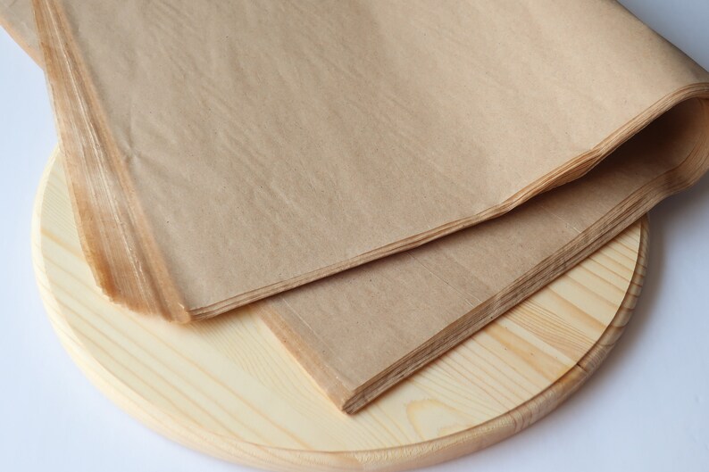 May include: A stack of brown tissue paper on a round wooden surface.