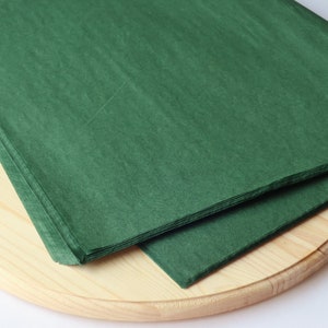 May include: A stack of green tissue paper on a wooden surface.
