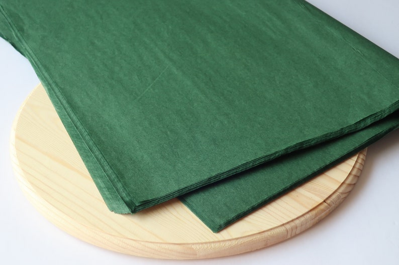 May include: A stack of green tissue paper on a wooden surface.