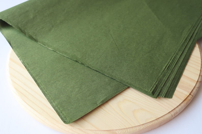 May include: A stack of green tissue paper on a wooden surface.