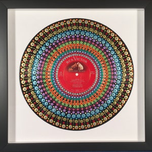 May include: A vintage vinyl record painted with colorful dots in a mandala design. The record label is red with the text "RCA Victor" and "New Orthophonic High Fidelity" in white. The record is framed in a black frame.