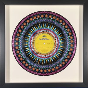 May include: A black vinyl record painted with a colorful mandala design. The record label is yellow and features the text "Deutsche Grammophon" and "Symphony No. 2 C minor Op. 36" in black text.
