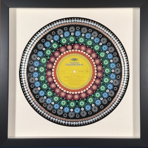May include: A black vinyl record painted with a colorful mandala design. The record label is yellow and features the text "Deutsche Grammophon" and "Symphony No. 2 D major, Op. 73".