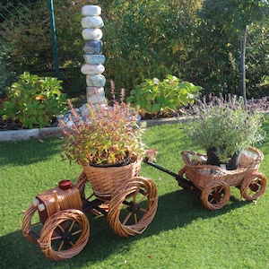 Peut inclure: Un chariot en osier tiré par un tracteur en osier. Les deux sont remplis de plantes en pot. Le chariot a une plante de lavande et le tracteur a une plante verte. Le chariot et le tracteur sont sur une pelouse verte.