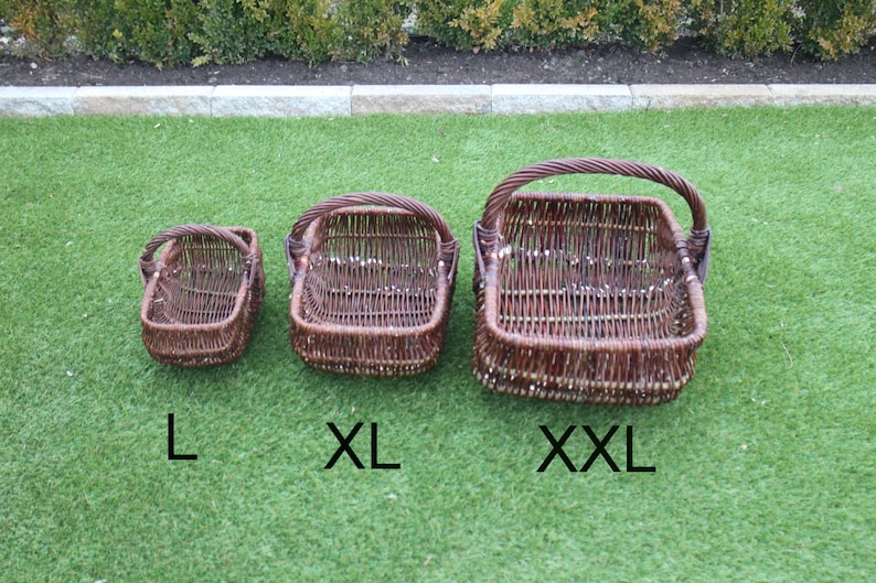 May include: Three brown wicker baskets with handles, labeled L, XL, and XXL. The baskets are on a green artificial grass surface.