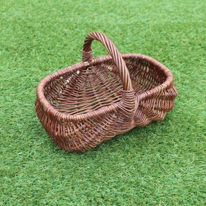 May include: A brown wicker basket with a handle. The basket is oval shaped and has a woven pattern.