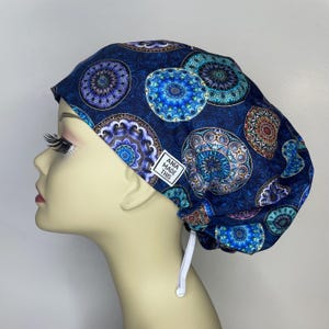 May include: Blue and white patterned surgical scrub hat with a tie string. The hat has a label that says "Ania Made This".