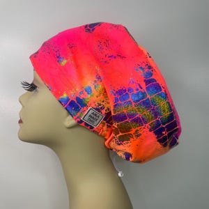 May include: A pink and orange surgical scrub hat with a holographic iridescent pattern and a blue and gold "ANIA MADE THIS" label.