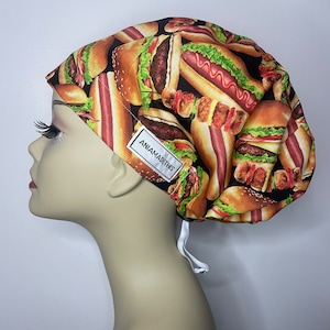 May include: A black scrub hat with a print of hot dogs and hamburgers. The hat has a white drawstring and a white label that says "AniAmadeThis".