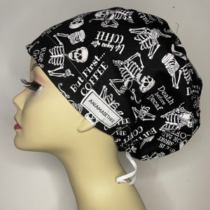 May include: Black and white patterned scrub hat with a skull and crossbones design and the text "But First... Coffee" and "Life begins after coffee".