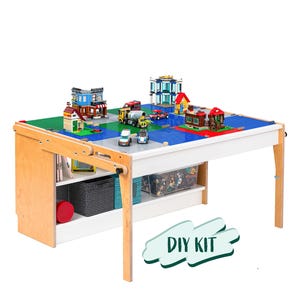 May include: A white and natural wood play table with a blue and green building block surface. The table features a storage shelf and is decorated with toy buildings, vehicles, and figures. The text "DIY KIT" is visible.