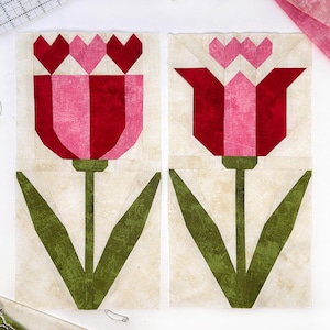 May include: Two fabric quilt blocks featuring tulip designs. Each block has a cream-colored background with a red and pink tulip, green stem and leaves. The tulip petals are geometric shapes, and the flower tops have heart-shaped accents.