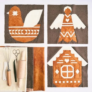 May include: Four fabric squares with brown and white patterned backgrounds. Each square features a different applique design: a bird, an angel, a house, and a gingerbread house. The designs are all in shades of brown and white.