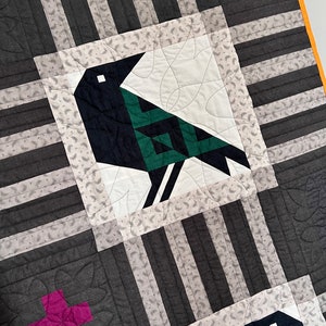 May include: A black and white quilt with a green and black bird design. The quilt is made of different fabrics and has a geometric pattern.