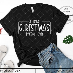 May include: Black t-shirt with white text that reads "Official Christmas Baking Team" in a white rectangle. The shirt is on a white surface with a pair of sandals, sunglasses, a pair of jeans, and a green leaf.