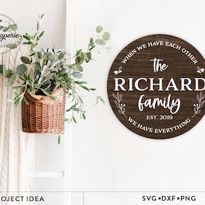 以下が含まれることがあります： 「When we have each other, the Richard family, est. 2019, we have everything」と書かれた茶色の木製看板。看板は白い花の模様で飾られています。
